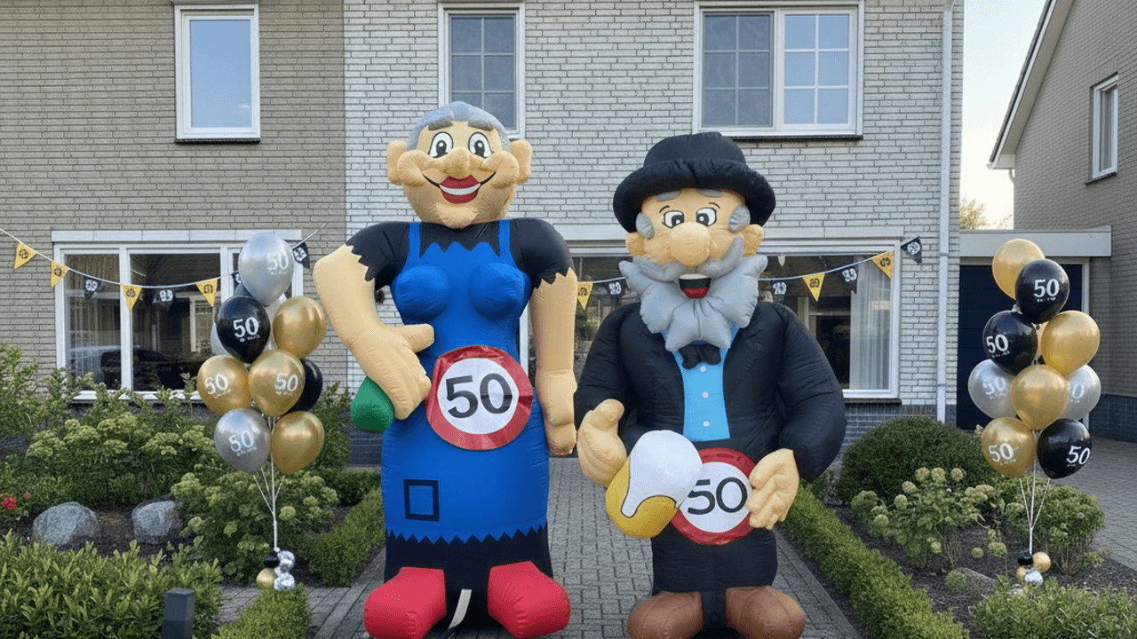 Grote opblaaspoppen van Abraham en Sarah met feestdecoratie in de tuin, inclusief ballonnen en slingers, ter ere van een 50e verjaardag.