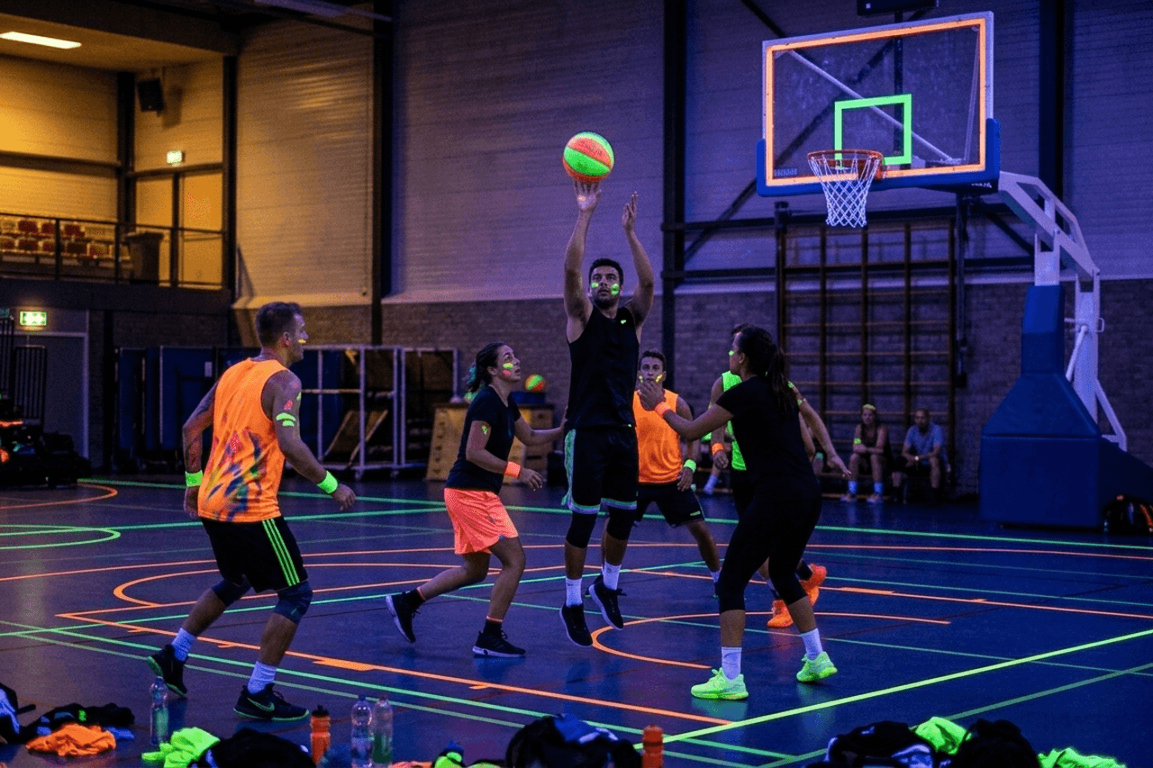 Glow in the dark basketbal in een sporthal met UV-verlichting en neonlijnen
