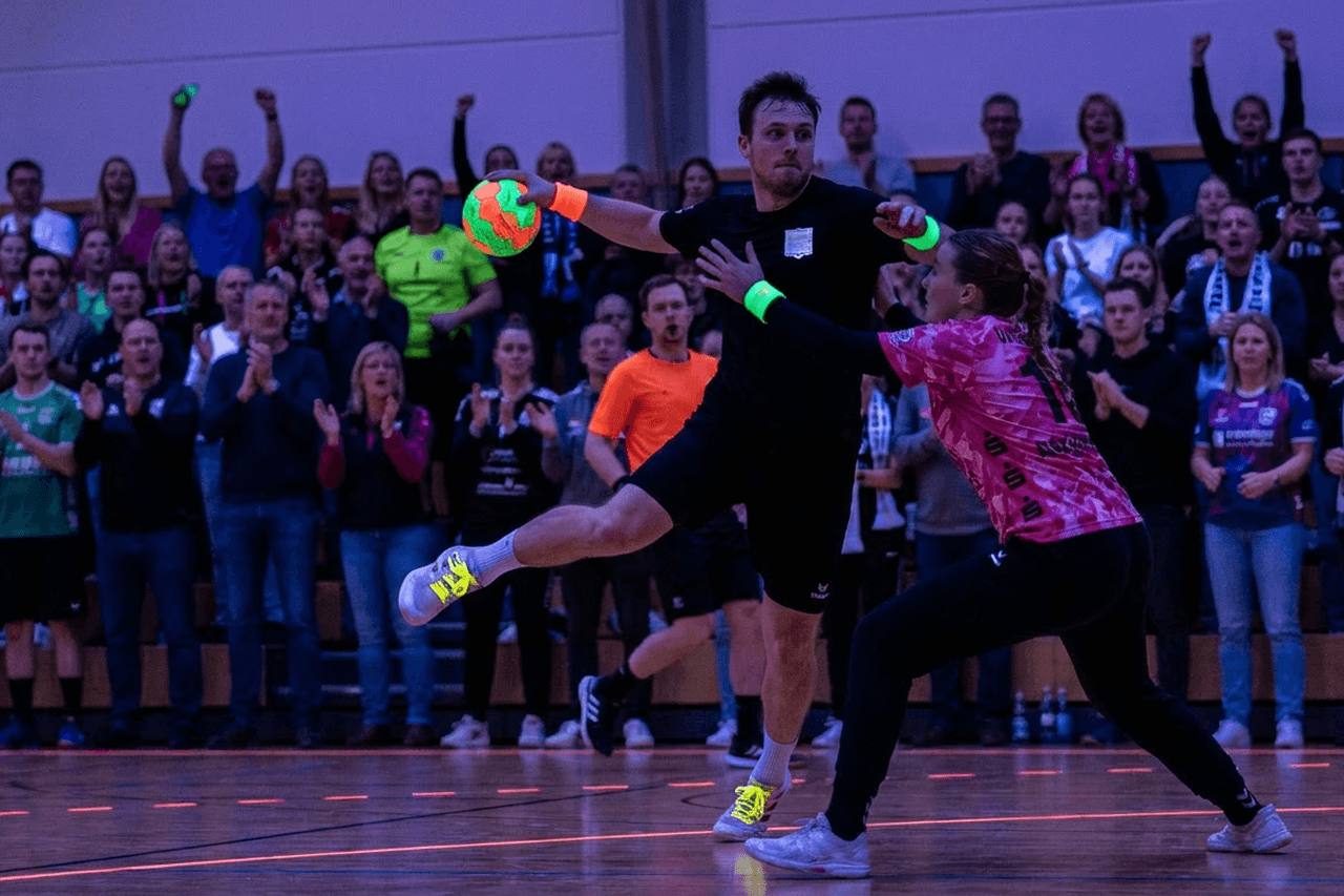 Glow in the dark handbal met UV-verlichting en neonlijnen op de baan